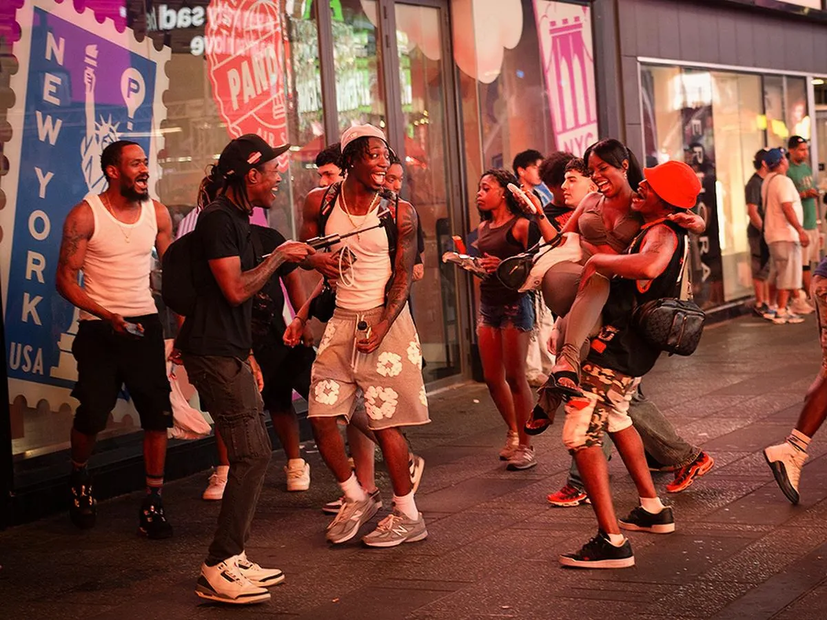 Group of young men dancing and celebrating in front of New York USA stamp mural on Times Square street