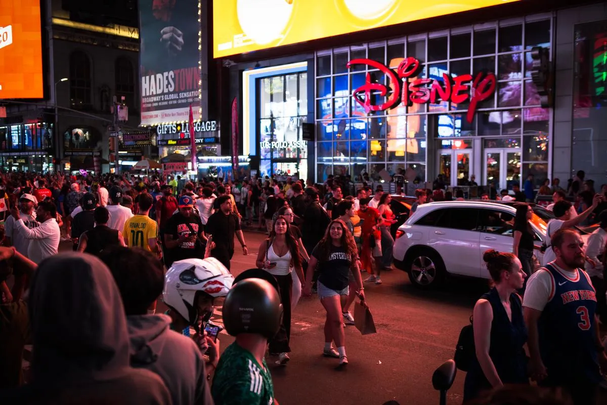 Night view of Times Square with Disney Store glowing and crowds of fans celebrating in the streets