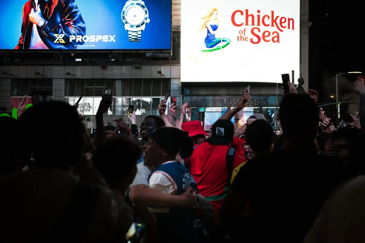Silhouetted crowd with raised phones and arms beneath Prospex watch and Chicken of the Sea billboards at night