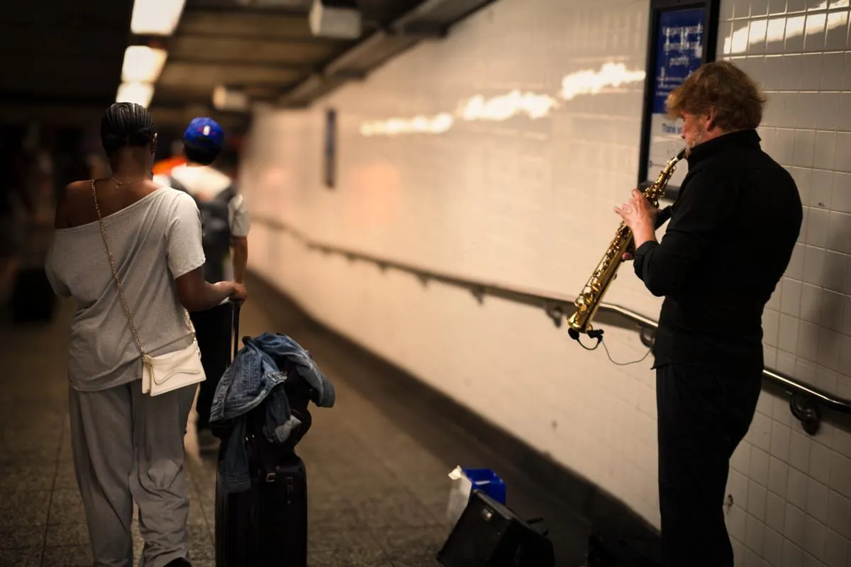 Saxophone player performing in subway station while commuters wait on platform