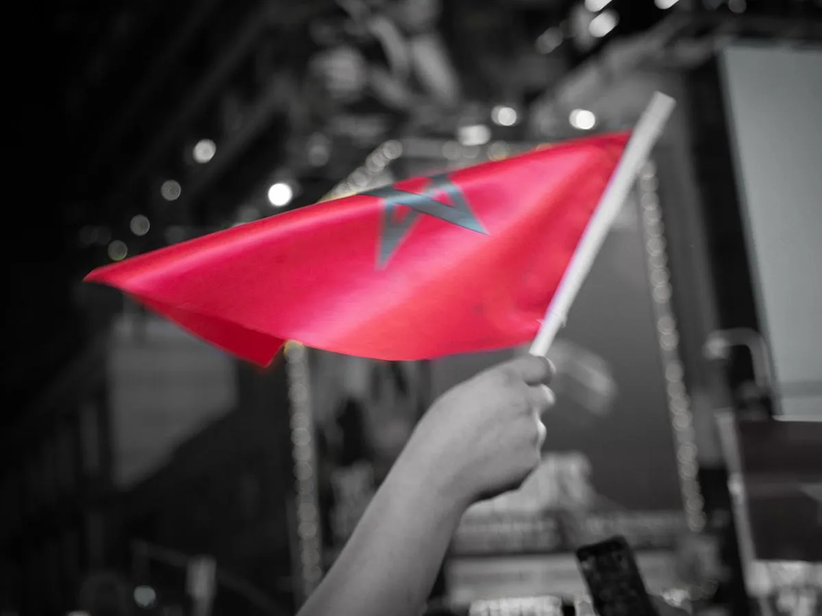 Artistic selective color photograph of a Moroccan flag with green pentagram star waving against a black and white Times Square background